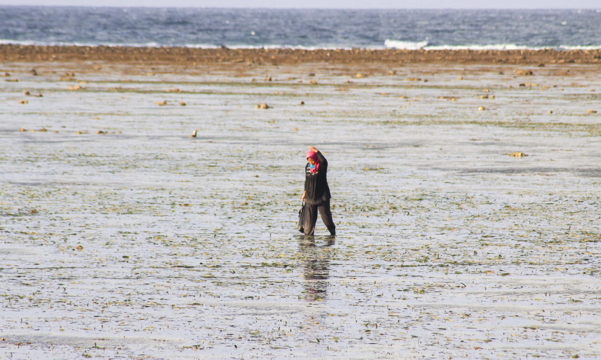 man in black jacket walking on low tide sea water