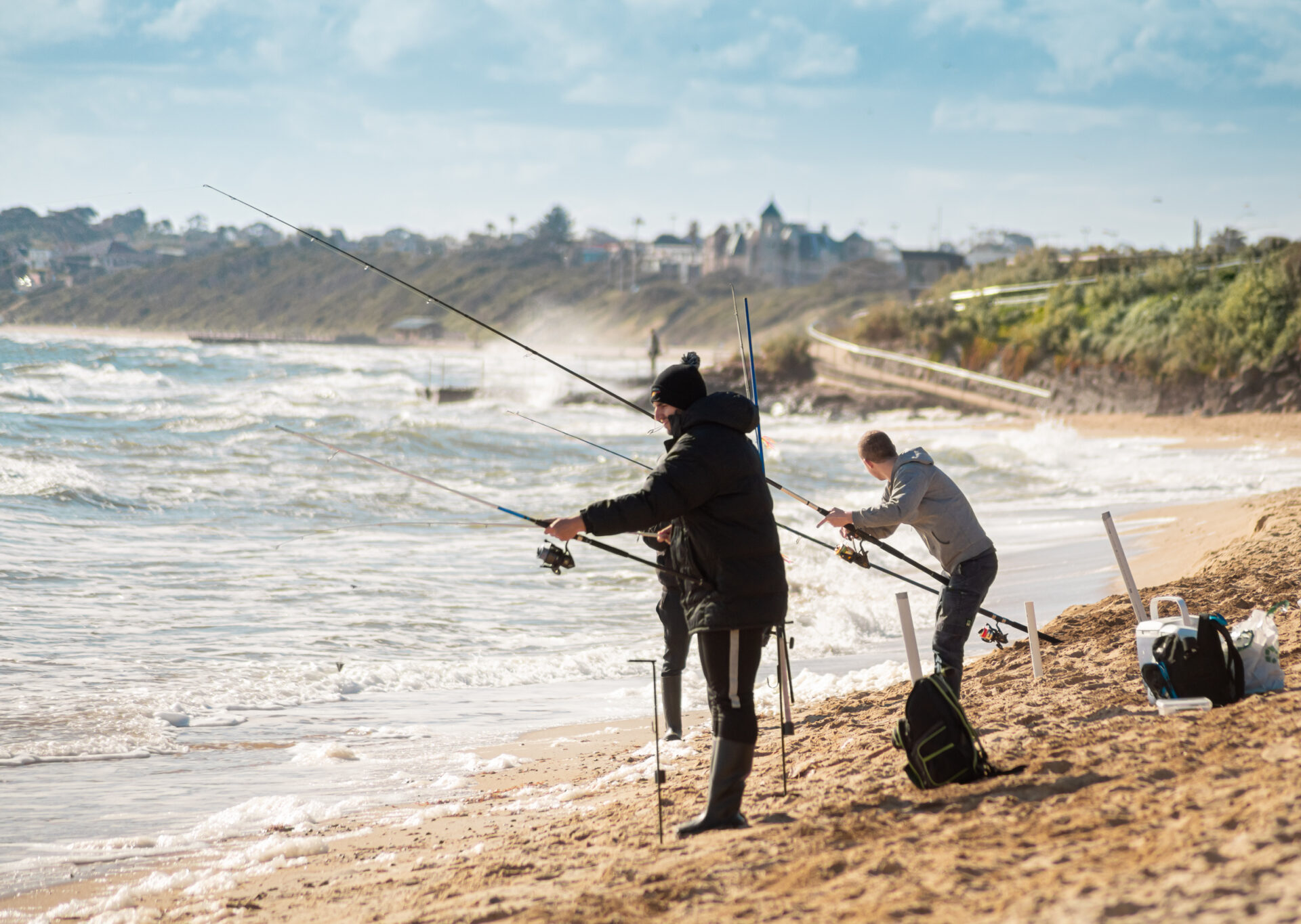 men standing on the beach with fishing rods. surf fishing in daylight