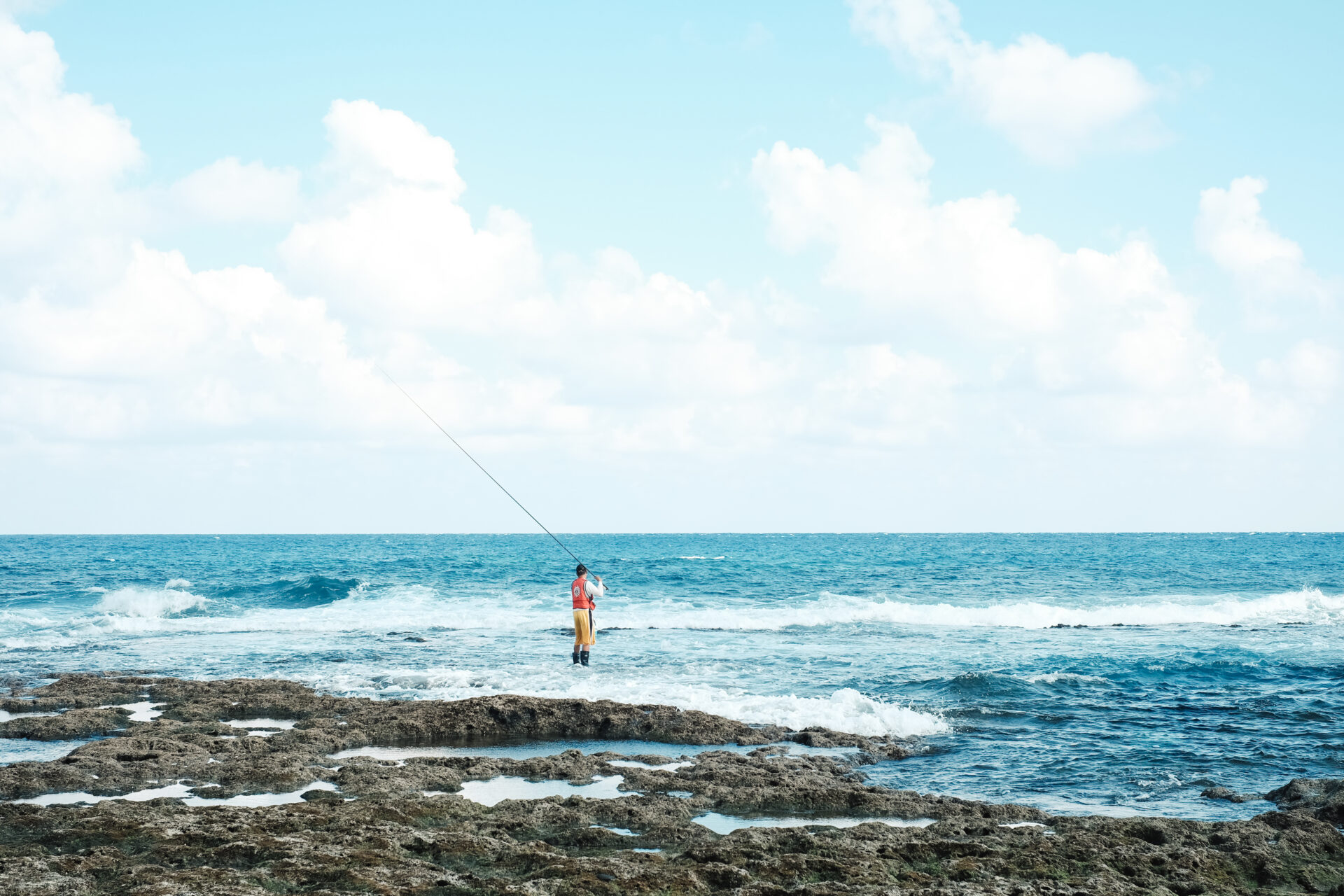 woman surf fishing from rocks near the shore